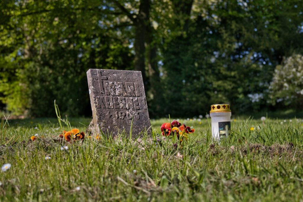 Grab mit wetterfestem Grabschmuck, Blumen und Laterne auf einem Friedhof